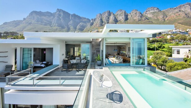 A modern house with a pool, a dining area, and a bedroom with a view of mountains. - Ethereal 4bed Camps Bay Villa Atlantic Reflection (Cape Town)