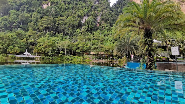 A swimming pool with clear blue tiles, surrounded by lush greenery and mountains in the background. - Mountain & Lake Views' Suite Cycas (Ipoh)