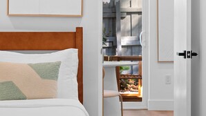 Un dormitorio con cabecera de madera, cama con ropa blanca y una obra de arte enmarcada en la pared.