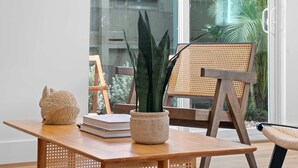 Una mesa de madera con una planta en maceta, una escultura tejida y una pila de libros.
