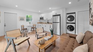 Una cocina moderna con armarios blancos, un refrigerador de acero inoxidable y una lavadora integrada.