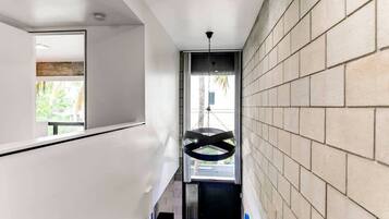 Un interior moderno con una pared de azulejos, un lámpara colgante y vistas al exterior a través de una ventana.