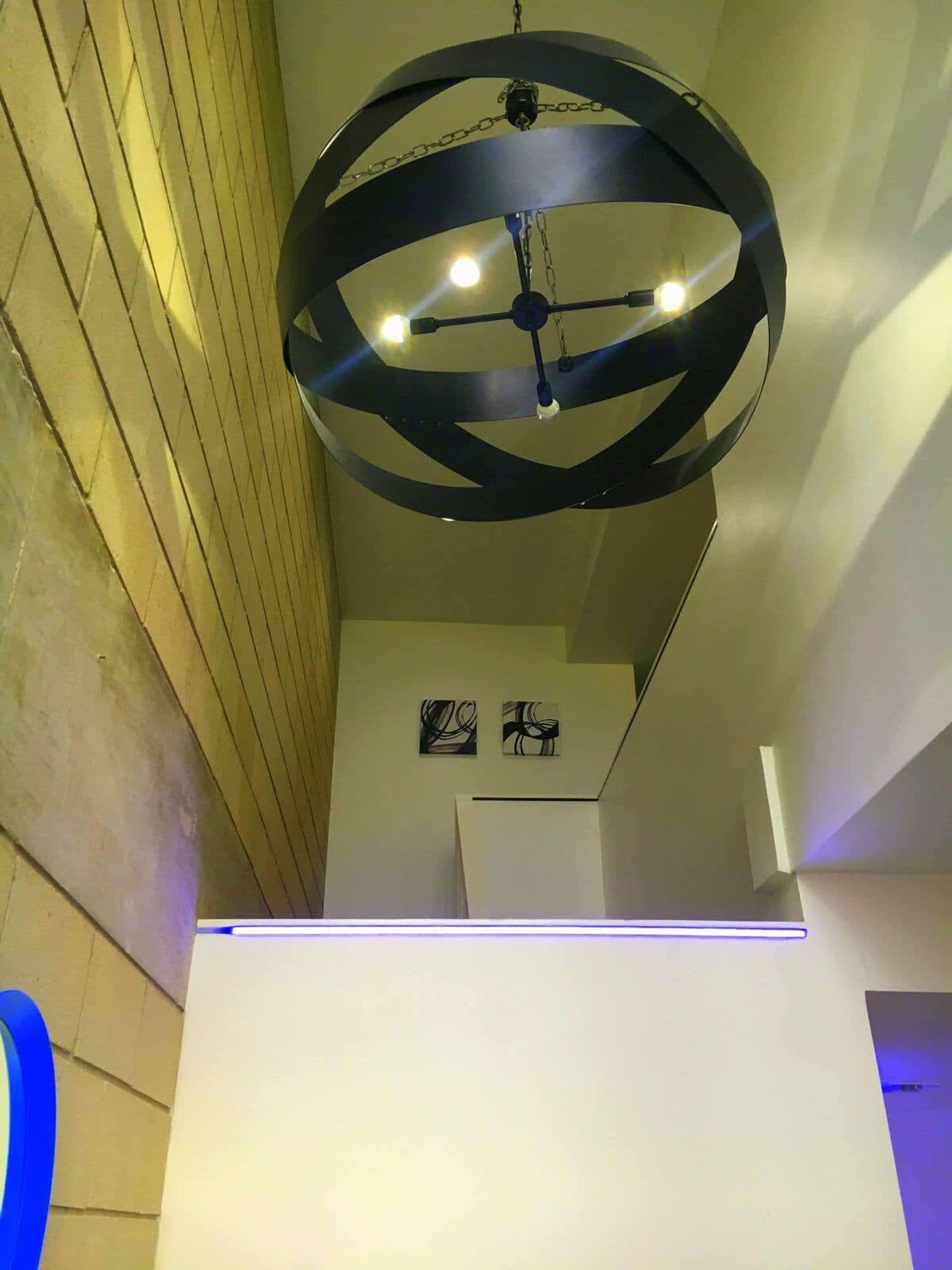 A modern interior with a circular ceiling light fixture and a white wall with abstract art.
