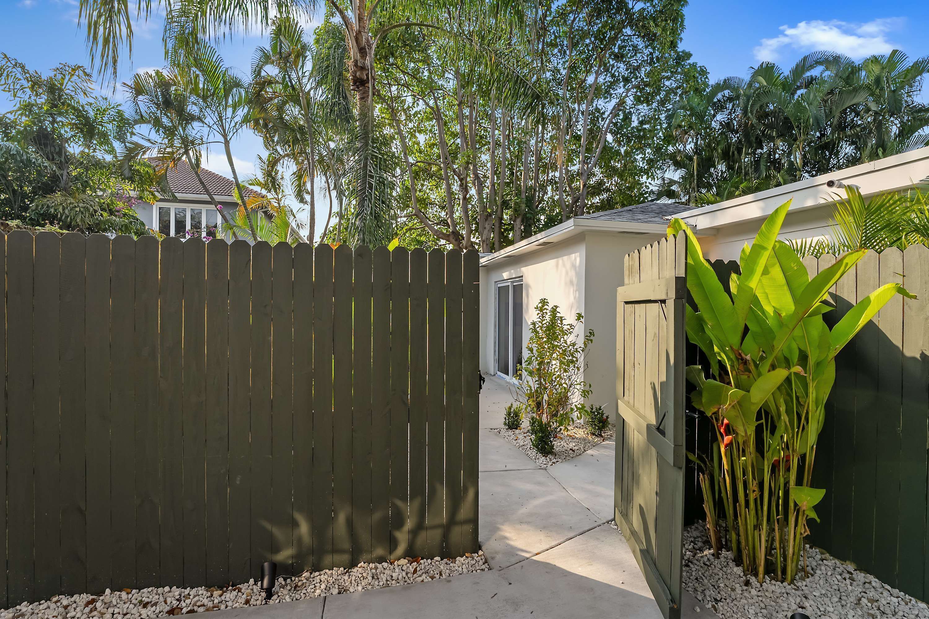 A residential property with a wooden fence, a small garden with plants, and a pathway leading to a door.