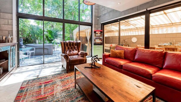 A modern living room with a leather sofa, a wooden coffee table, and a red rug. - Singer House on the Water (Fort Lauderdale)
