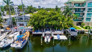 A marina with boats docked, surrounded by lush greenery and modern buildings. - Singer House on the Water (Fort Lauderdale)