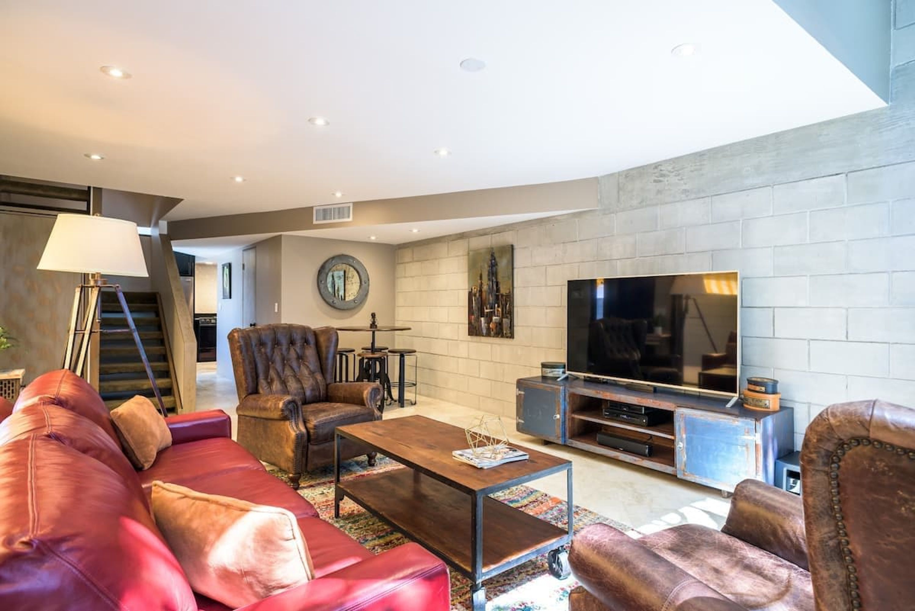 Una sala de estar moderna con un sofá de cuero, una mesa de centro, un televisor y una chimenea.