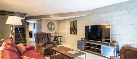 Una sala de estar moderna con un sofá de cuero, una mesa de centro, un televisor y una chimenea.