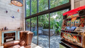 A room with a leather chair, a slot machine, a fireplace, and a view of the outdoors. - Singer House on the Water (Fort Lauderdale)