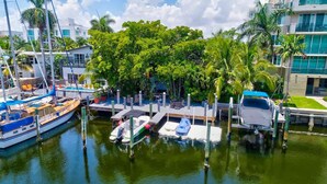 A marina with boats docked, surrounded by lush greenery and modern buildings. - Singer House on the Water (Fort Lauderdale)