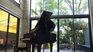 A grand piano in a spacious room with large windows and a view of greenery outside. - Piano House on the Water (Fort Lauderdale)