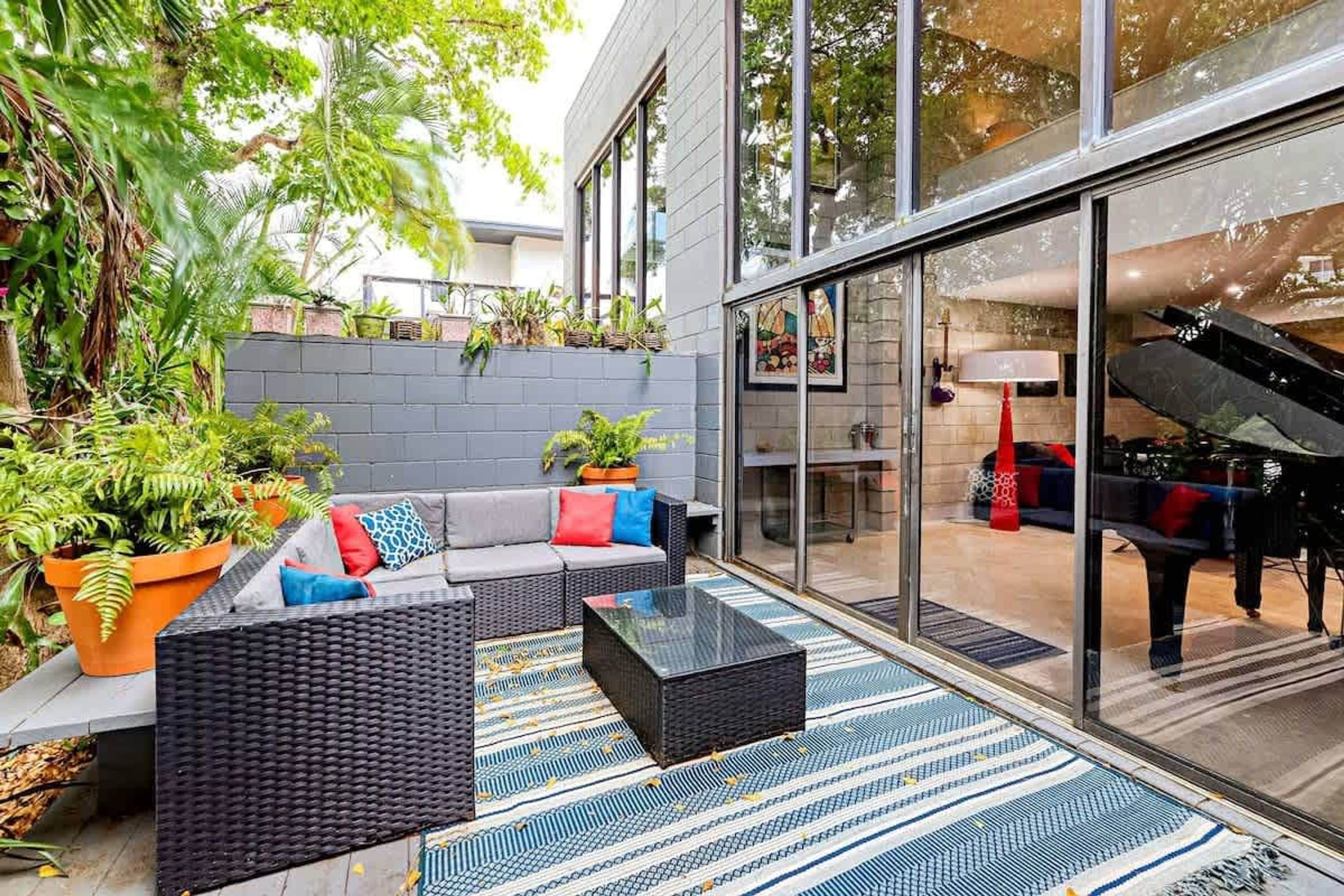 A modern outdoor living area with a sofa, coffee table, and potted plants.