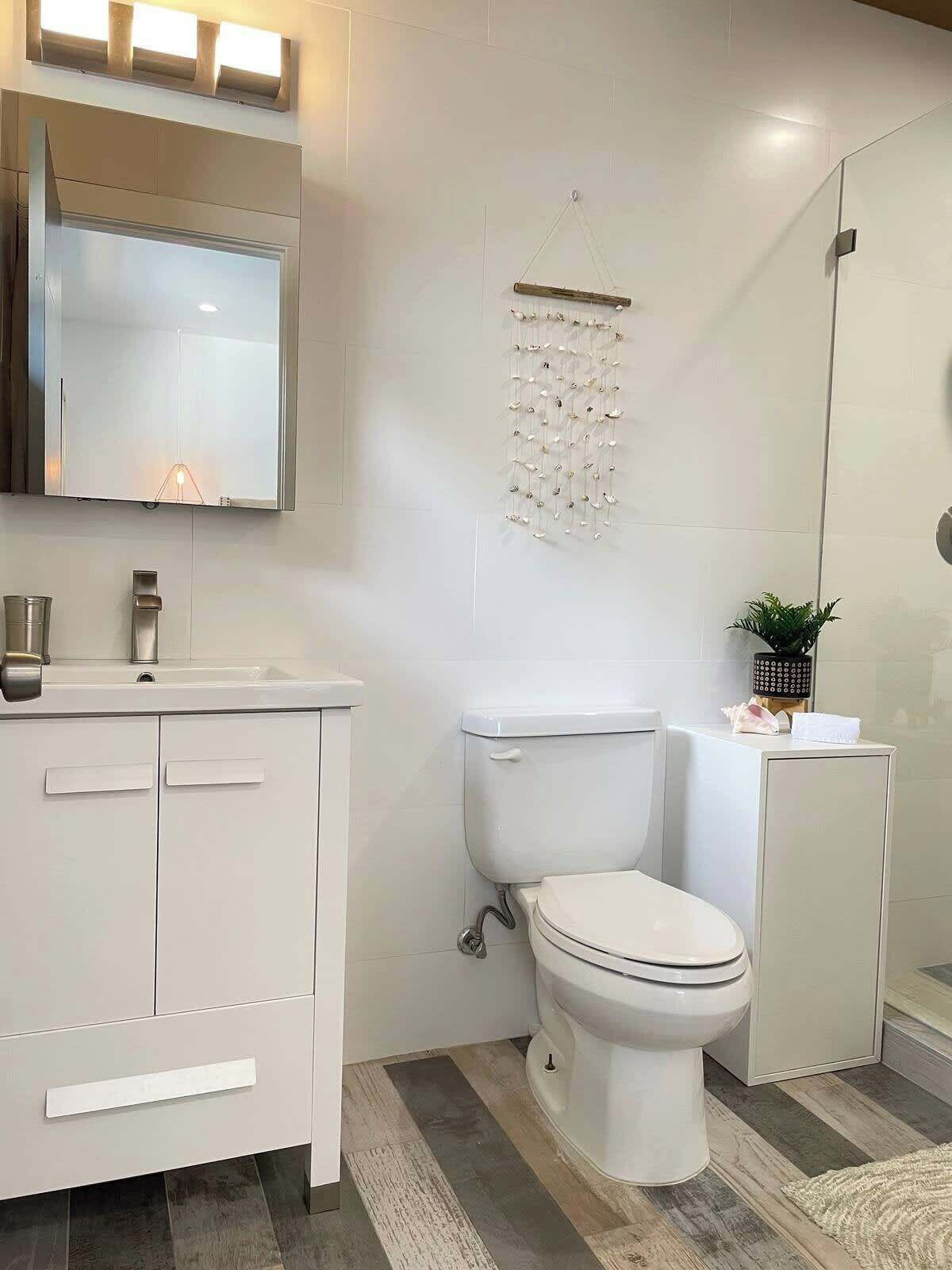 Ein modernes Badezimmer mit weißem Waschtisch, Toilette und Duschbereich.