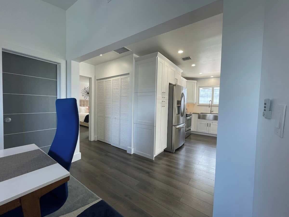 A modern kitchen with white cabinets, a stainless steel refrigerator, and a built-in oven.