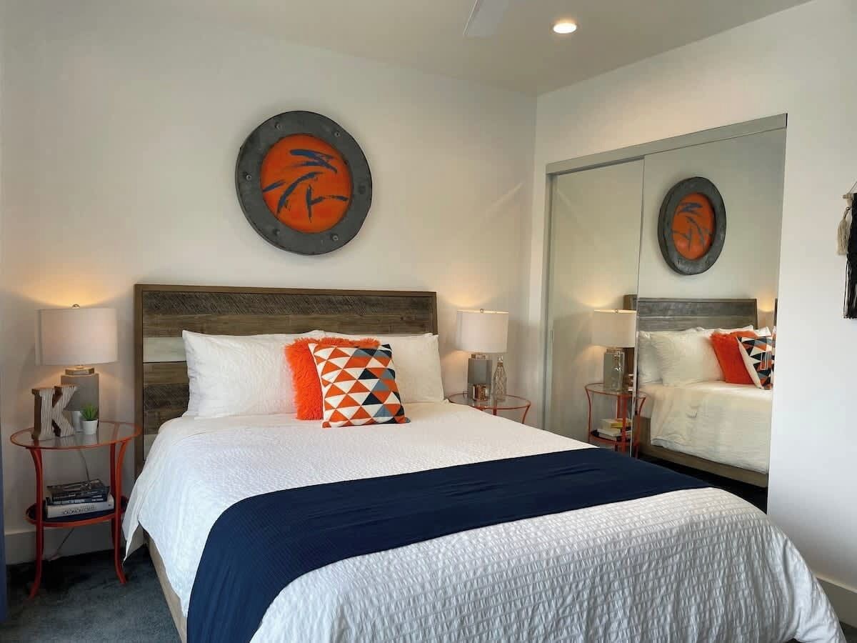 A hotel room with a large bed, two bedside tables, a mirror, and artwork on the walls.