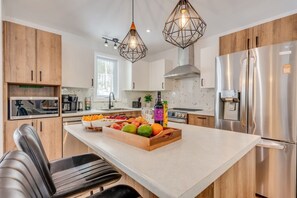 A modern kitchen with a central island, stainless steel appliances, and wooden cabinetry. - Amira | Nature Retreat | Hiking (Brownsburg)