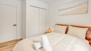 Ein Schlafzimmer mit einem Bett, einem Nachttisch, einer Lampe und einem Gemälde an der Wand.