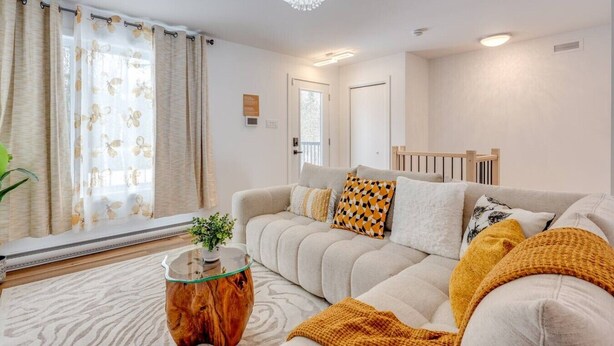 Ein stilvolles Wohnzimmer mit einer Couch, Zierkissen, einem Glastisch und einer Kristallleuchter.