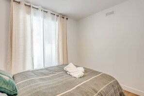 Ein Schlafzimmer mit einem Bett, Vorhängen und einem Wandlüfter.