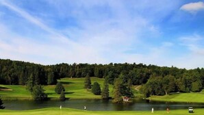 Ein Golfplatz mit See, Bäumen und blauem Himmel.
