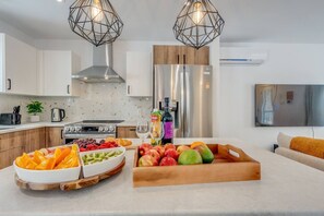 Una cocina moderna con una isla central, electrodomésticos de acero inoxidable e iluminación colgante.