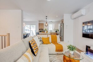 Una sala moderna con un sofá, una mesa de centro de vidrio y una chimenea.