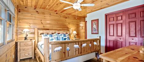 A wooden cabin bedroom with a bed, dresser, and a table.