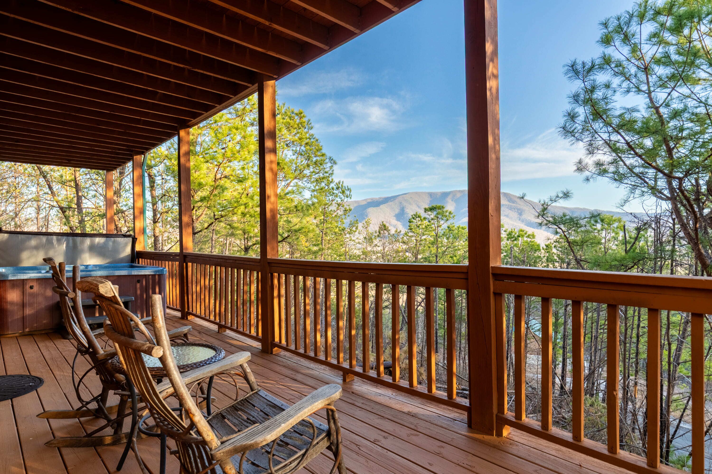 Una terraza de madera con mobiliario exterior y vistas a un paisaje montañoso.