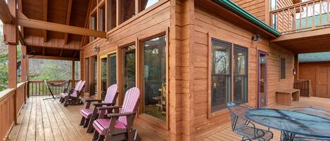 A wooden cabin with a deck, large windows, and outdoor seating.