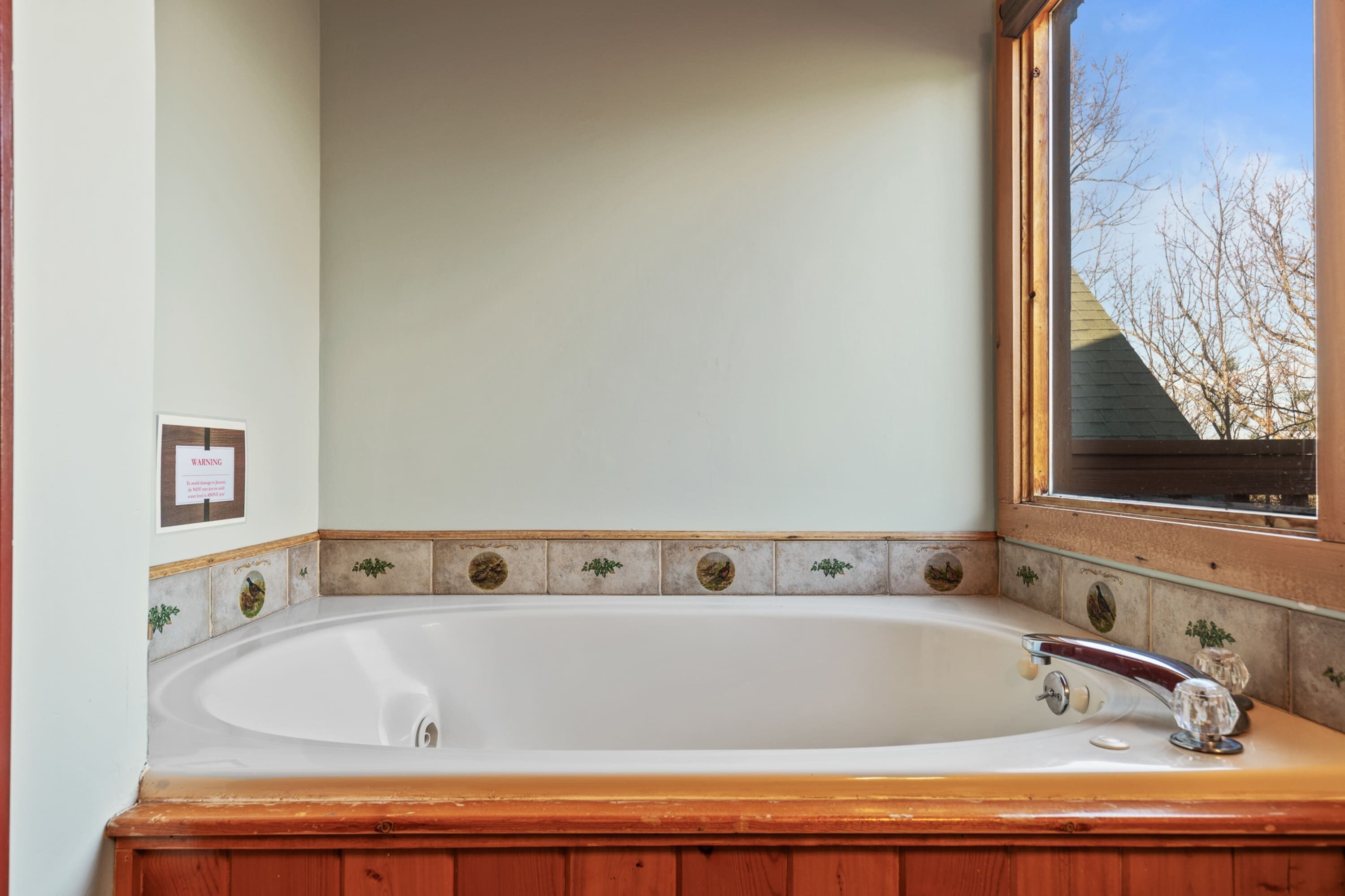 A bathroom with a freestanding bathtub, a wooden vanity, and a window with a view of trees.