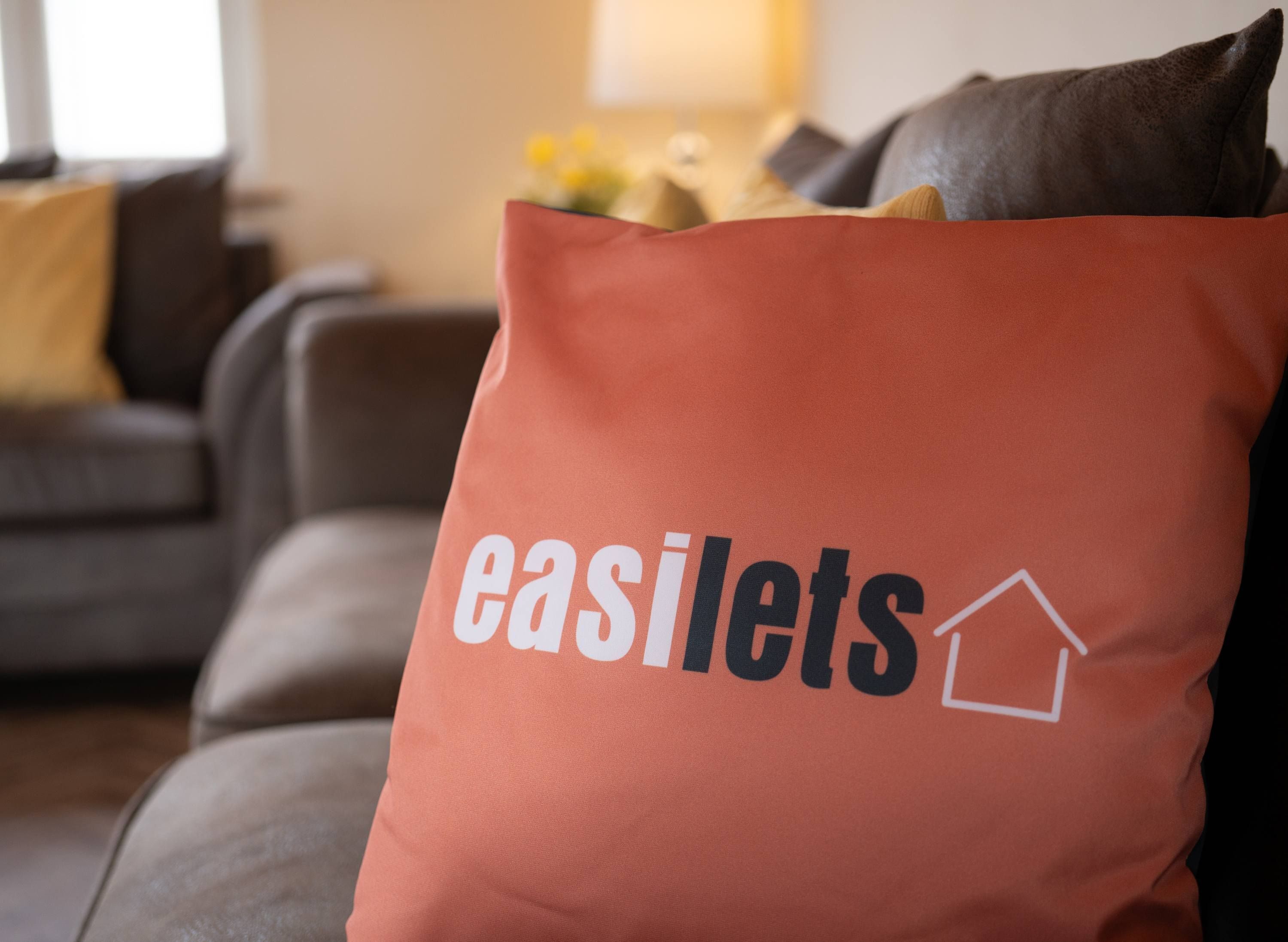 A living room with a sofa, cushions, and a bag with "easilets" logo.