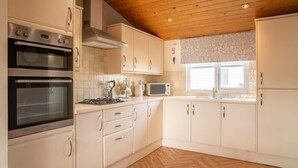 Une cuisine équipée de deux fours, d’un four à micro-ondes, d’une cuisinière et de meubles de rangement blancs.