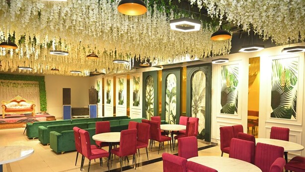 A hotel lobby with green sofas, red chairs, and round tables. - NRI Hotel (Barara)