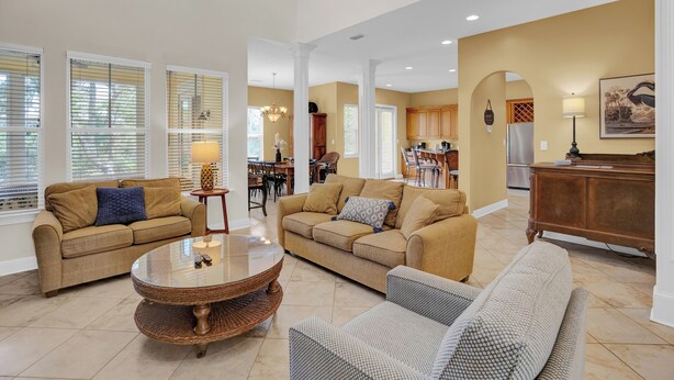 A spacious living room with two sofas, a coffee table, and a dining area with a chandelier.