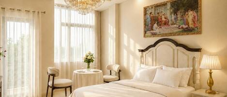Une chambre à coucher avec un grand lit, un lustre, une table ronde ornée d’un vase de fleurs et un tableau accroché au mur.
