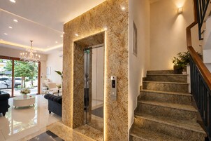 Un hall de hotel con un mostrador de recepción de mármol, una escalera y vistas al exterior.