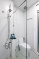 Um banheiro moderno com box de vidro, vaso sanitário e pia.