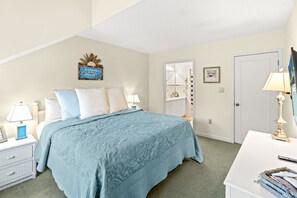 Une chambre à coucher avec un lit, des tables de chevet, un bureau et une porte.