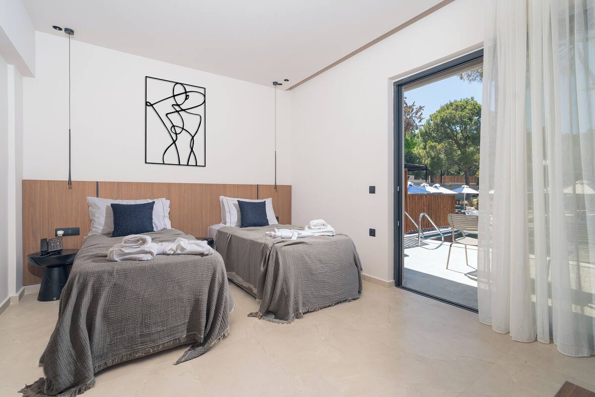 A modern bedroom with two beds, a large window, and a view of an outdoor pool area.