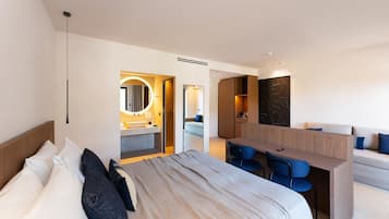 A modern hotel room with a bed, a desk, a sofa, and a bathroom.