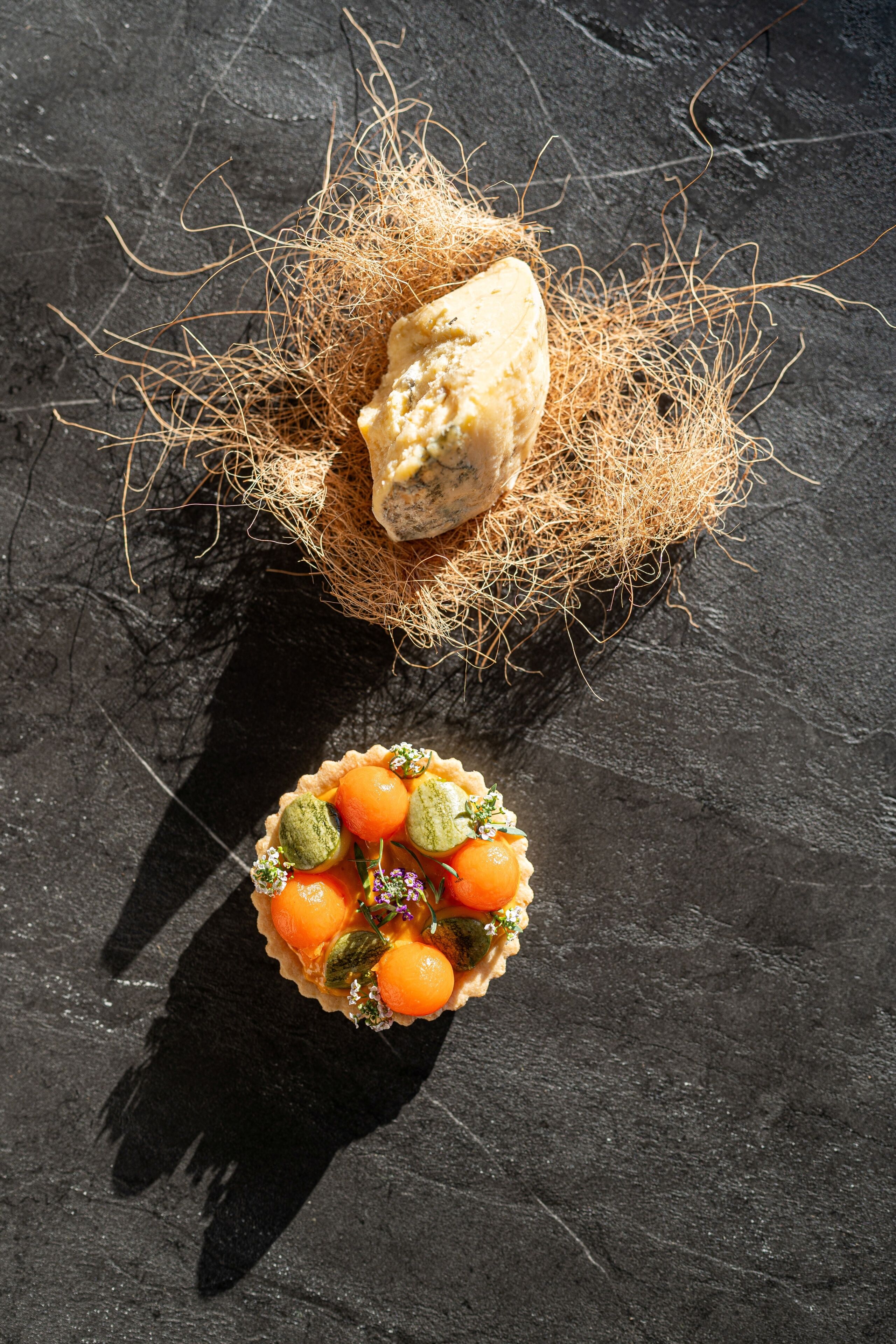 A dessert with a coconut shell and a tart with fruit and nuts.