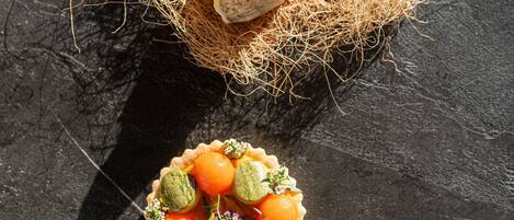 A dessert with a coconut shell and a tart with fruit and nuts.
