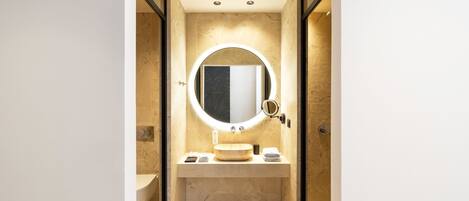 A modern bathroom with a round mirror, a sink, and a toilet.