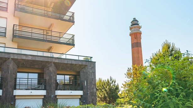 A modern building with a lighthouse in the background.