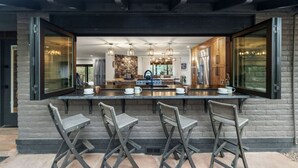 Una cocina moderna con una isla grande, taburetes de bar y un salpicadero de piedra.