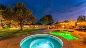 Un patio trasero con piscina, un área de patio con sillones de descanso y una casa al fondo.