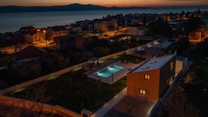 A residential area with a swimming pool, houses, and a view of the sea at dusk. - Villa Dide Moga Zadarvillas (Sveti Filip i Jakov)