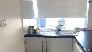 Una cucina funzionale con lavatrice, cestino e finestra che lascia entrare luce naturale.