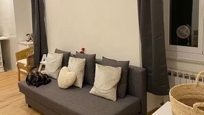 A modern living room with a grey sofa, white cushions, and a wicker basket on a white table. - Bocca di rosa in centro (La Spezia)