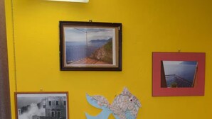 Una habitació amb una paret groga, un mapa emmarcat i diverses fotografies emmarcades.